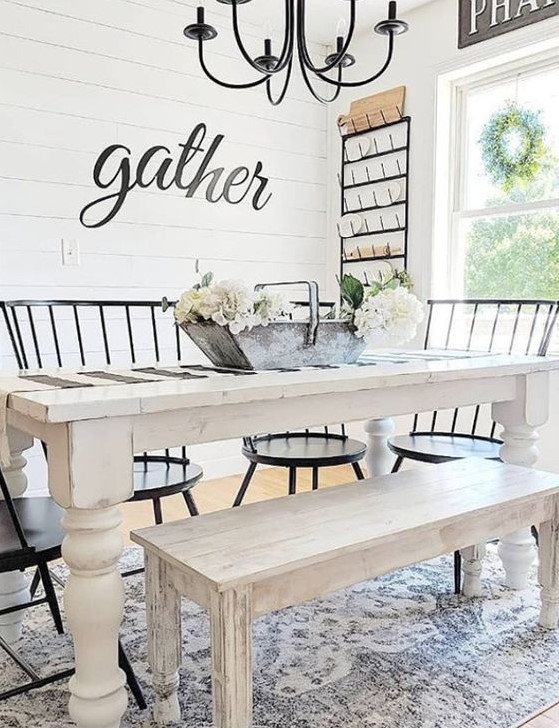 an airy and welcoming farmhouse dining room with a white dining set, black chairs, a black chandelier and much light