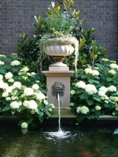 an elegant vintage fountain with a bowl with greenery on top and a large pool or pond for flowing in is a lovely idea for an elegant vintage inspired garden