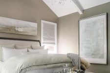 an exquisite greige bedroom with a grey vintage wooden bed wiht neutral bedding and a bench, a wave chandelier and artwork