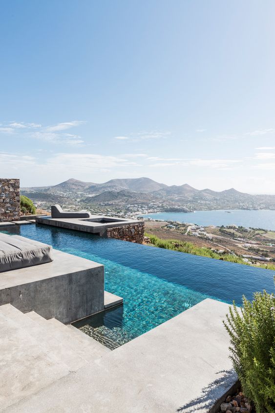 an infinity pool with a gorgeous sea and green view, a concrete deck and steps is a lovely space to spend time and have a rest