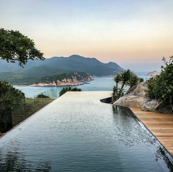 an infinity pool with a sea view, with a catchy curved to let the trees grow naturally is a lovely space to have a rest in