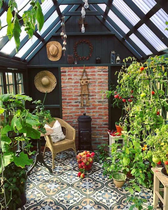 an orangery she shed clad with tiles, with black walls, some plants and vegetables and a chair plus a hearth
