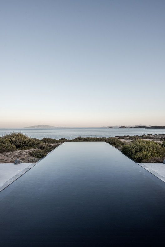 an ultra-minimalist infinity pool with a sea and greenery view, with a stone deck is a gorgeous spot to spend time in
