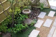 grass, concrete tiles, shrubs, a thin tree, a stone bowl fountain and rocks for a lovely and chic Japanese-inspired look