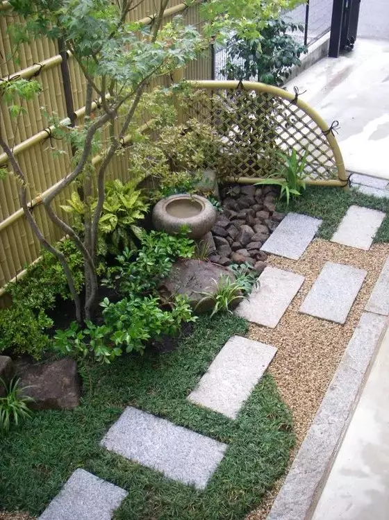 grass, concrete tiles, shrubs, a thin tree, a stone bowl fountain and rocks for a lovely and chic Japanese-inspired look