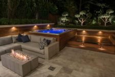 this hydropool self cleaning hot tub features a retaining wall, creating a sense of intimacy, a comfortable seating area with a fire pit