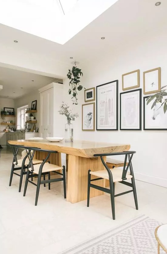 a Scandinavian dining space with a wood slab table, chic mid-century modern chairs, an elegant monochromatic gallery wall