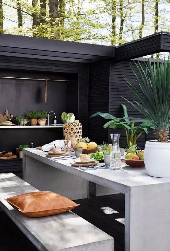 a Scandinavian outdoor kitchen and dining space with a concreye table and benches, a floating kitchen countertop