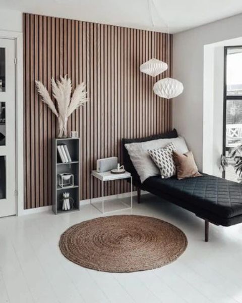 a Scandinavian space with a black lounger, a lightweight nightstand and a storage unit, pendant lamps and a jute rug