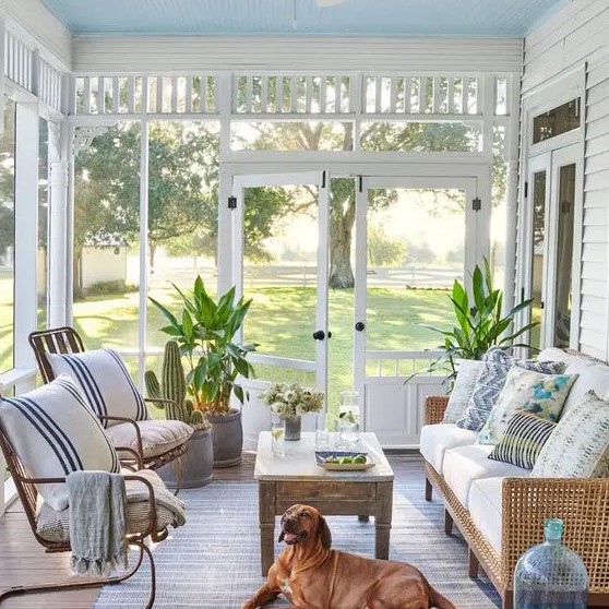 a beachy sunroom with rattan furniture, printed textiles, a wooden table and some potted plants