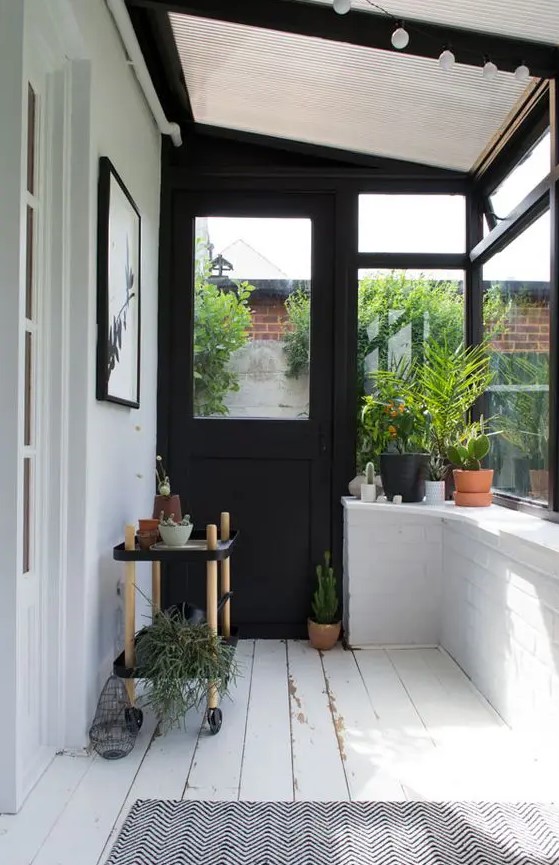 a black and white Scandinavian sunroom with a glass ceiling, lights and lots of greenery to make it double as an orangery