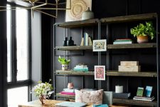 a black home office with paneled walls, a dark floral ceiling, a shelving unit, a beautiful desk and a grey chair