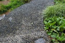 a black pebble garden pathway done with chaotical pattern looks very relaxed and very chic
