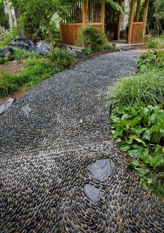 a black pebble garden pathway done with chaotical pattern looks very relaxed and very chic