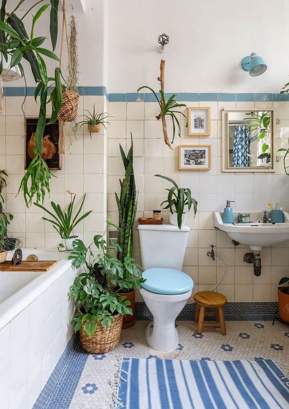 a boho bathroom with a mini gallery wall and an artwork over the bathtub is a cool idea, and touches of blue make it catchier