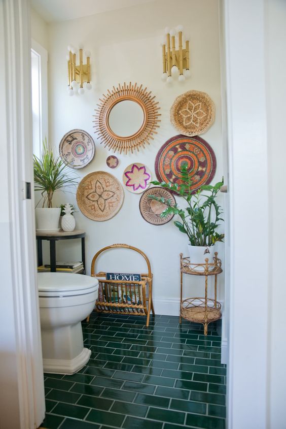 a boho bathroom with an emerald tile floor, a bold decorative basket gallery wall and some potted plants is a lovely space