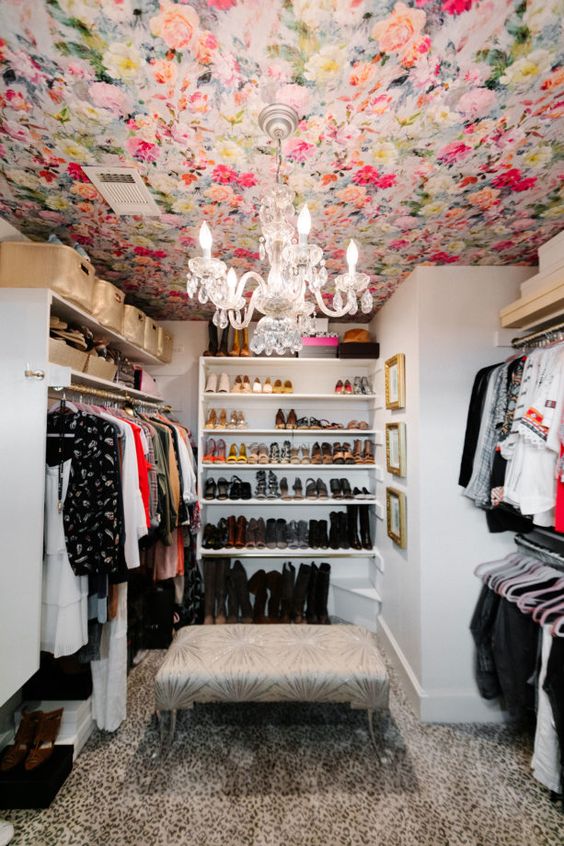 a bold closet with a colorful floral wallpaper ceiling, holders, shelves and racks for clothes and shoes