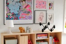 a bold gallery wall with bright posters and watercolors in black and white frames to give more color to the space