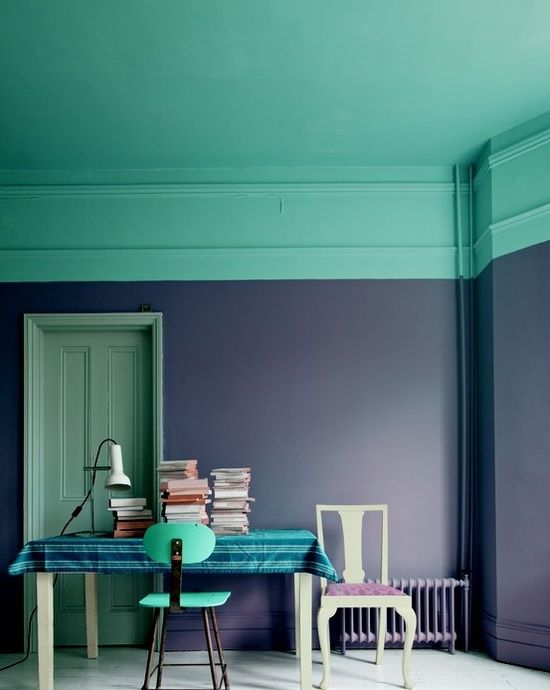 a bold home office with violet walls, a mint green ceiling, a desk and a mint chair and stacks of books