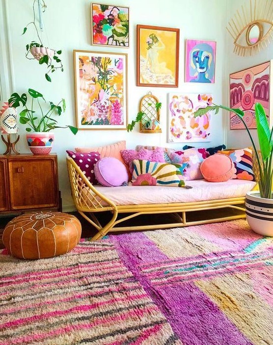 a bright and colorful gallery wall with mismatching frames, bold floral and naive artworks and greenery is a cool idea for a boho space