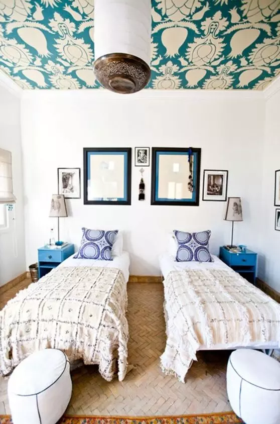 a bright double guest bedroom with a bright wallpaper ceiling, the prints of which match the pillows