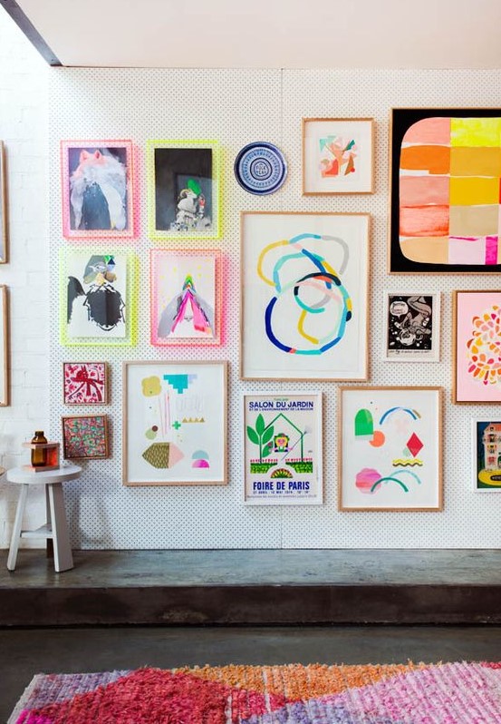 a bright gallery wall with abstract artworks and prints, with neon light frames and usual ones for a funky look