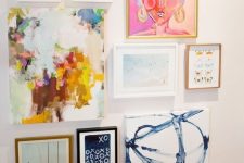 a bright gallery wall with mismatching frames and bright artworks is a bold and cool idea for a bright space