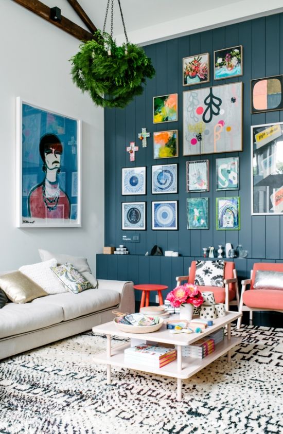 a bright living room with a teal accent wall, coral chairs, a colorful gallery wall and potted greenery is wow