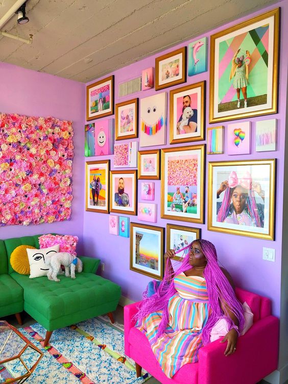 a bright living room with lilac walls, a colorful gallery wall with family pics and bright artwork and posters