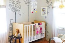 a bright nursery with a bold yellow ceiling, murals on the walls, light stained furniture and a printed rug and some lovely toys