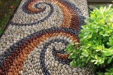 a bright pebble path with blue, white, burgundy and rust pebbles and swirl patterns
