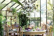 a bright vintage sunroom with refined wooden furniture, an oversized chandelier and potted greenery, colorful textiles