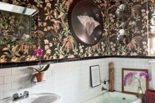 a catchy bathroom with dark wallpaper on the walls and ceiling, white subway tiles and a tub, a free-standing sink and some art