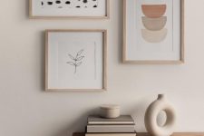 a chic and serene space with a stained credenza, a peaceful and soothing mini gallery wall of prints, a vase and books