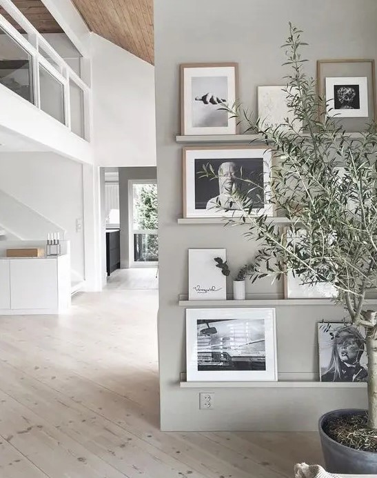 a chic contemporary gallery wall with grey ledges on a matching wall, black and white photos in mismatching frames