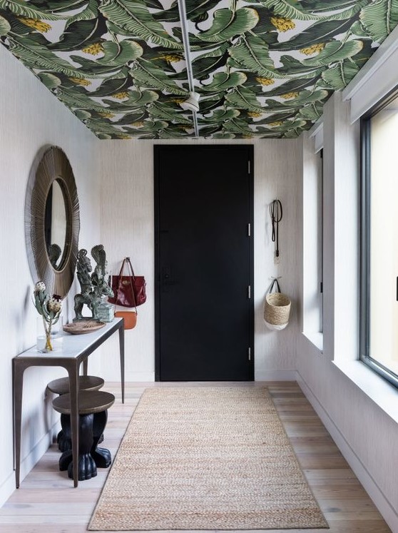 a chic entryway made bold with a banana leaf print wallpaper ceiling that adds print and color to make the space chic