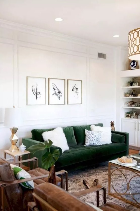 a chic mid-century modern living room with built-in shelves and cabinets, a green sofa, brown leather chairs, chic tables and a mini gallery wall