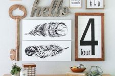 a chic mid-century modern gallery wall with a rustic feel – signs, a wooden key, some artworks and calligraphy is chic
