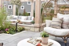 a chic neutral modern outdoor space with a corner sofa, a rattan chair, wooden chairs, a round concrete table