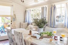 a chic vintage to shabby chic sunroom with white shabby furniture, striped curtains, greenery and a rustic lamp