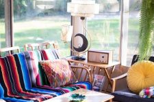 a colorful boho sunroom with rattan furniture, colorful upholstery and pillows, a coffee table and some string lights