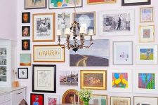 a colorful floor to ceiling gallery wall, a vintage rich-stained table and matching vintage chairs, a chic chandelier over the space
