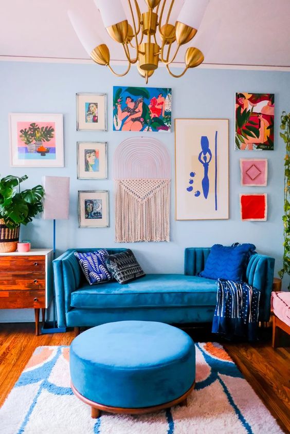 a colorful living room with lots of blue, with a bright and catchy gallery wall that includes macrame is wow