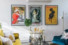 a colorful mid-century modern living room with a mustard sofa, a navy chair, a color block rug and a bright vintage poster gallery wall