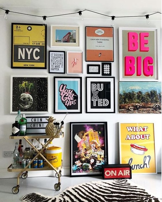 a colorful pop art gallery wall in various colors - posters for fun and with black and white frames is a bold idea