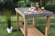 a concrete and wood outdoor table with potted greenery can be used for many things including serving drinks