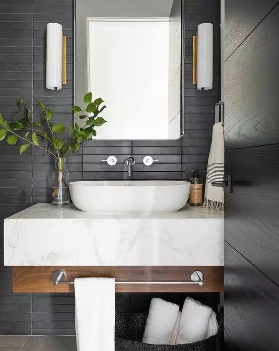 a contemporary bathroom with matte black skinny tiles on the wall plus a floating wood and marble vanity