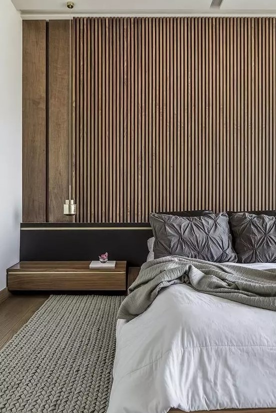 a contemporary bedroom with a wood slat accent wall, a black bed with extended headboard, neutral bedding and a floating nightstand