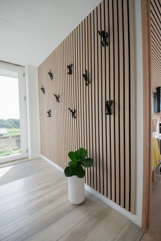 a contemporary entryway with a wood slat with decor and a potted plant is a lovely and cool space filled with light