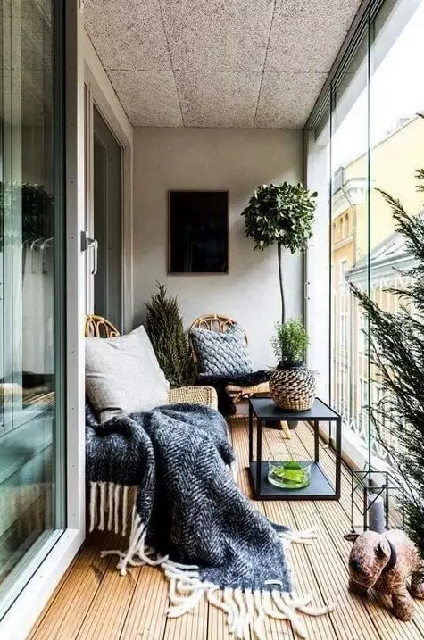 a contemporary sunroom with a boho feel - a couple of wicker loungers, a table, a lantern and potted greenery